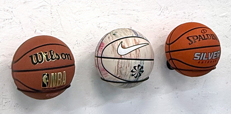 Close-up of three basketballs on the wall.